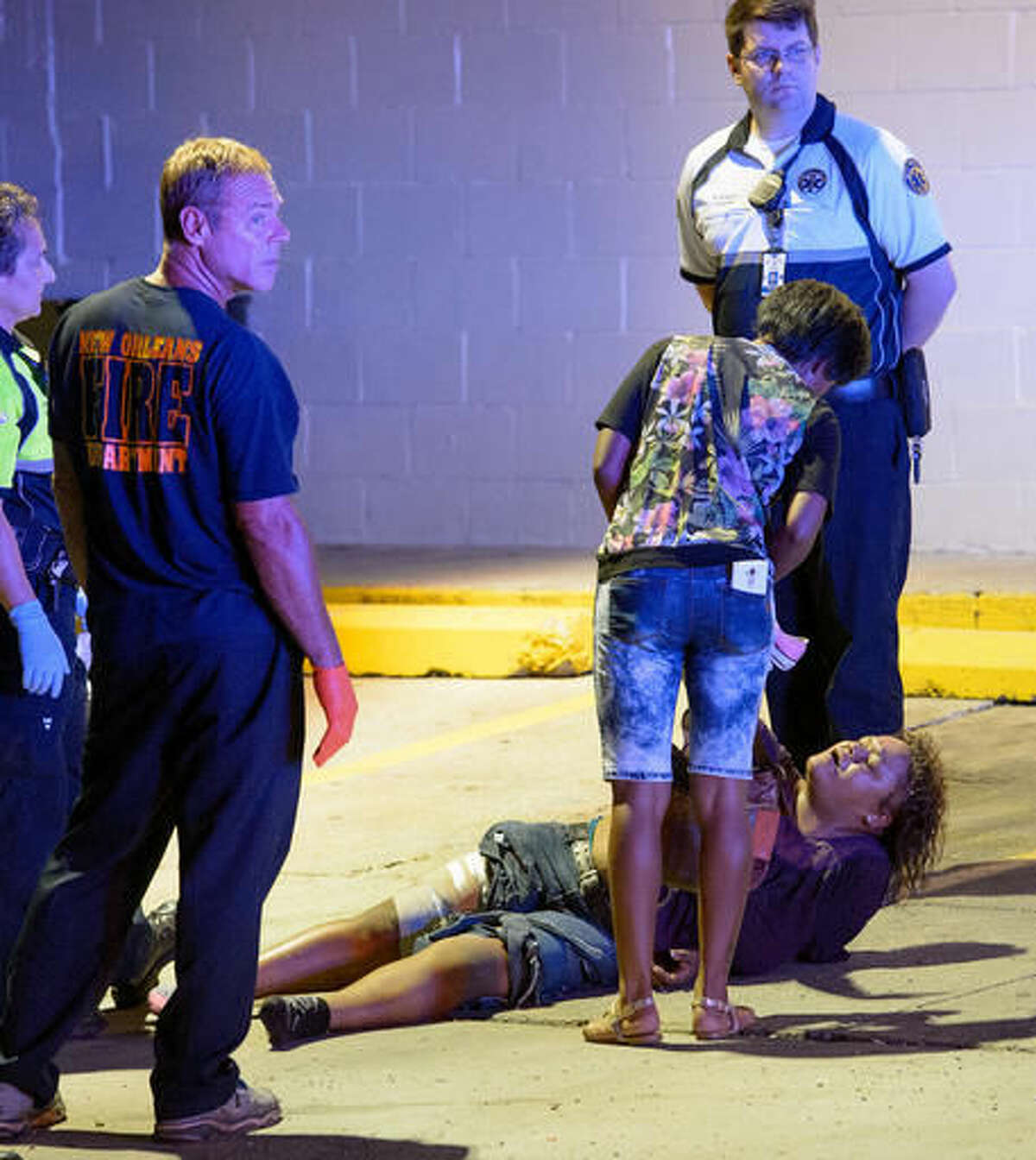 New Orleans Police Department, Fire Department, and EMS personnel respond to an injured woman at the scene of shooting where multiple people were shot, near First and South Derbigny St. in New Orleans, La. Sunday, Sept. 11, 2016. NOPD said they were working a triple shooting in the area. The woman was transported from the scene via ambulance. (Matthew Hinton/The Advocate via AP)