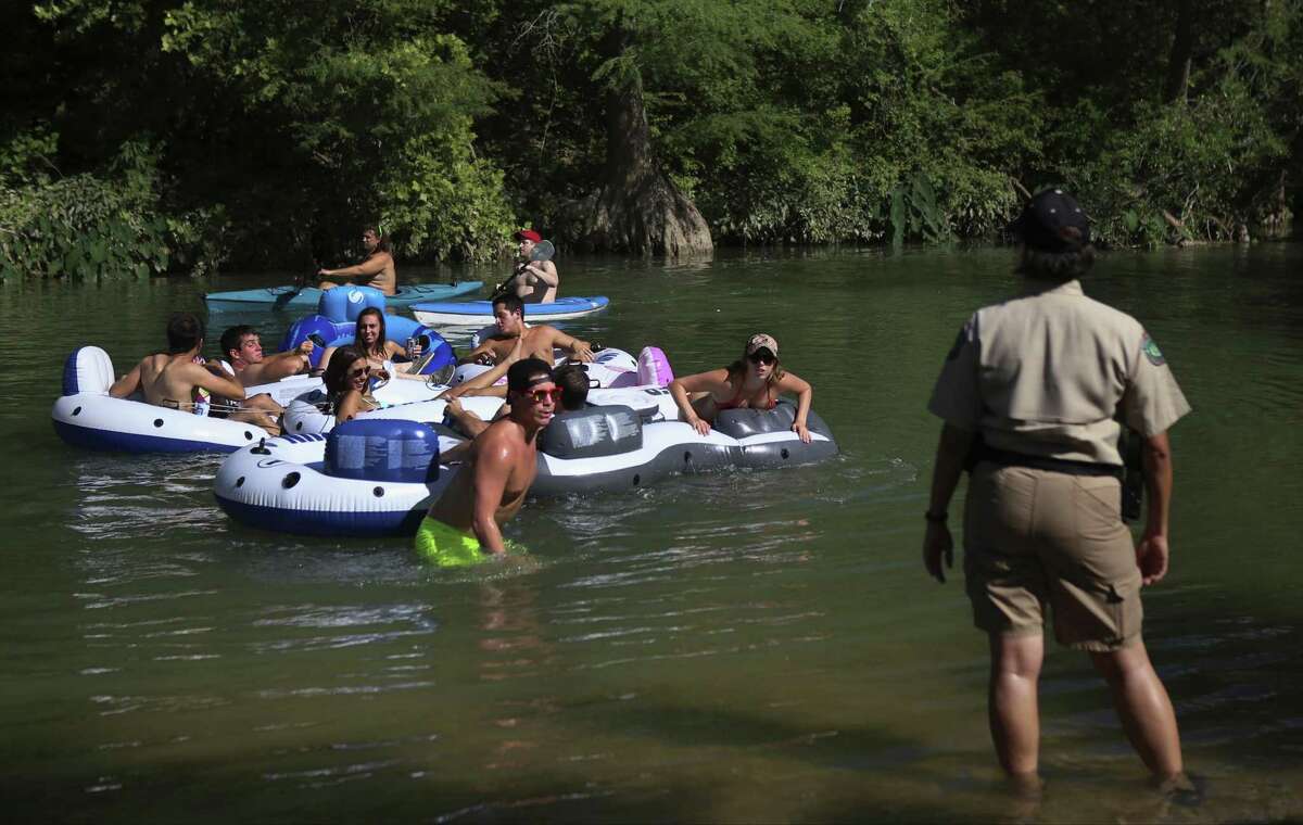 Texas Game Warden Joann Garza-Mayberry, right, calls over a group of tubers on the San Marcos River near the San Marcos River Retreat in San Marcos, Texas, on Thursday, June 5, 2014.