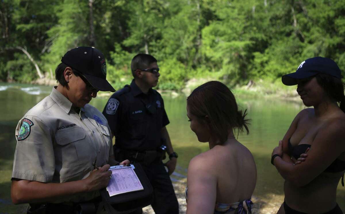 Texas Game Warden Joann Garza-Mayberry writes a ticket to a tuber on Thursday, June 5, 2014, at the San Marcos River near the San Marcos River Retreat in San Marcos, Texas.