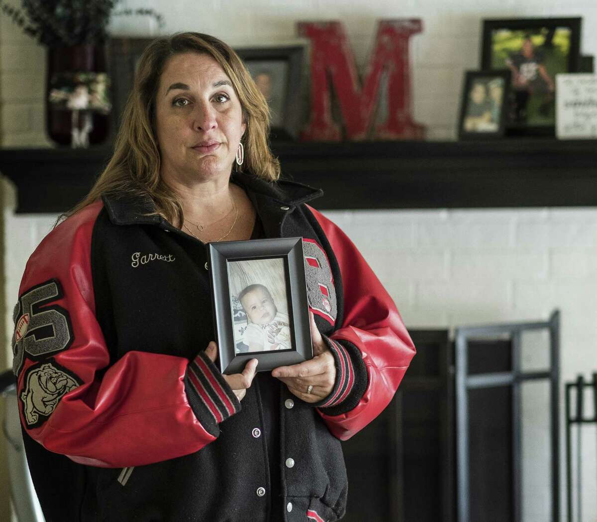 September 23, 2016 - Sherene Mayner, mother of Garrett McKinney wearing her son's letterman jacket holds a baby picture of him at her home in Austin, Texas, on Friday, Sept. 23, 2016. Mayner's son McKinney was shot and killed by a DPS Trooper in Paris, Texas, on September 21, 2015, after an altercation. McKinney, was a former Bowie high school football payer, and also diagnosed with schizophrenia. (AUSTIN AMERICAN-STATESMAN / RODOLFO GONZALEZ)
