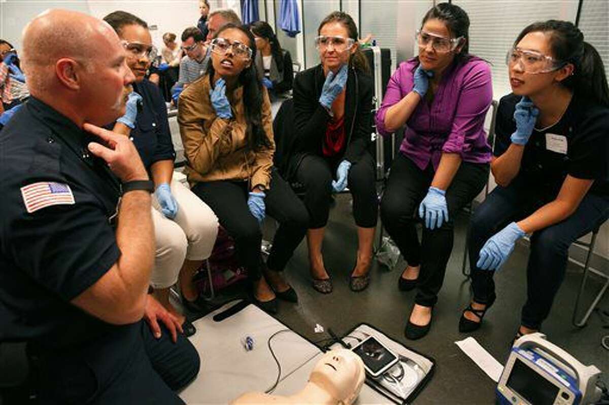 In this Aug. 22, 2016 photo, Steve Engle, left, with the North Kitsap Fire Department, instructs first-year medical students in health-care provider CPR during their first day of classes in Seattle. The students, from left, were Elizabeth Richards, Mahlet Assefa, Amanda dos Santos Thomas, Wendy Coard and Grace Pak. The course is supported by the Resuscitation Academy, a Seattle-based nonprofit designed to improve survival from cardiac arrest. (Erika Schultz/The Seattle Times via AP)