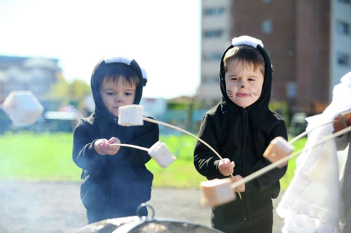 Three-year-old twins Preston, right, and Henry Updike toast marshmallows during the Mill River Park Spooktacular in Stamford, Conn. on Sunday, Oct. 23, 2016.