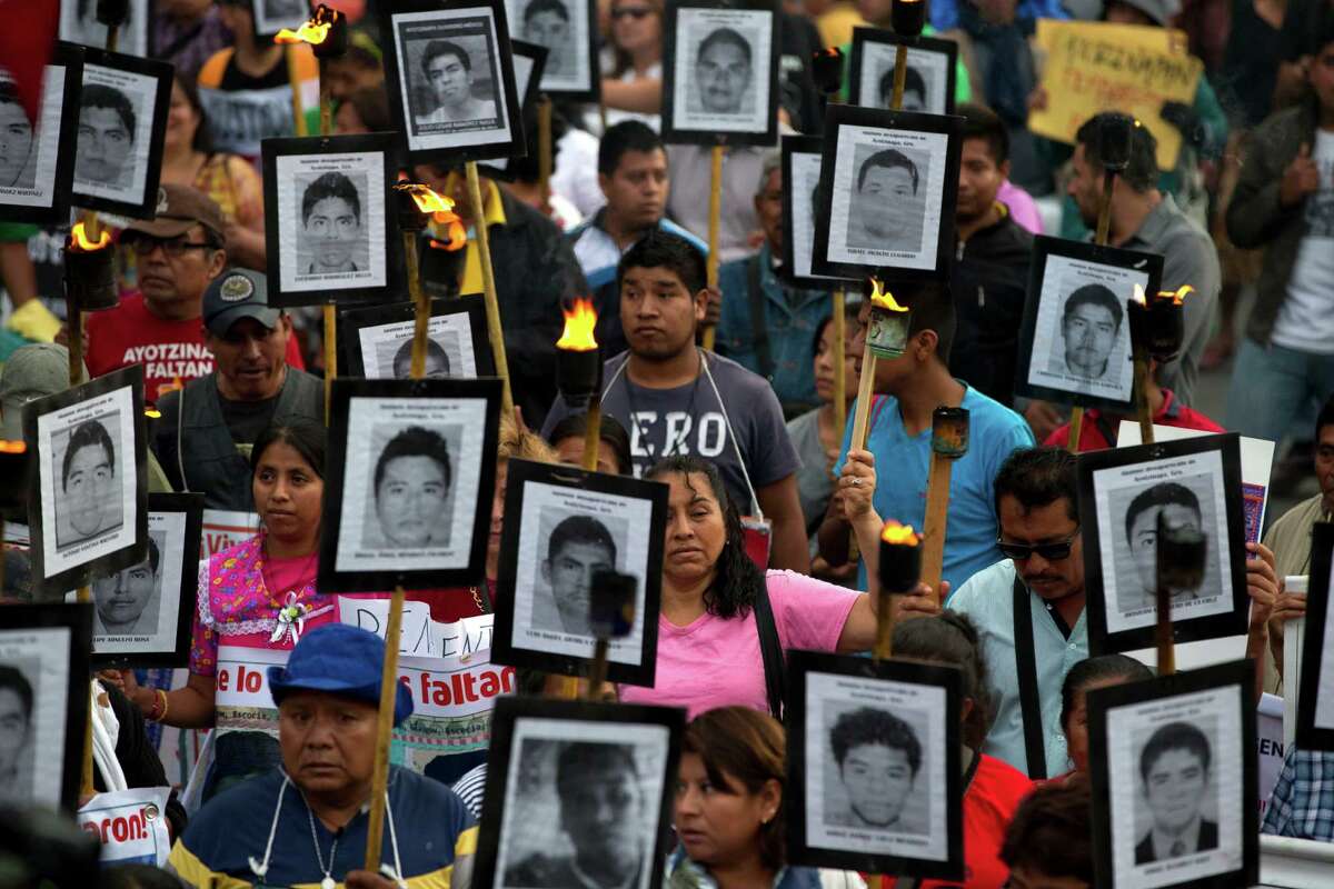 FILE - In this April 26, 2016 file photo, family members and supporters of 43 missing teachers college students carry pictures of the students as they march to demand the case not be closed and that experts' recommendations about new leads be followed, in Mexico City. The most recent forensic investigation of the southern Mexico garbage dump where the government says 43 students were incinerated did not confirm there was a fire there that night. It shows the experts found evidence the Cocula dump had been the site of at least five fires, but could not determine when. Remains of 17 people were also found, but it was unknown when they were burned. (AP Photo/Rebecca Blackwell, File)