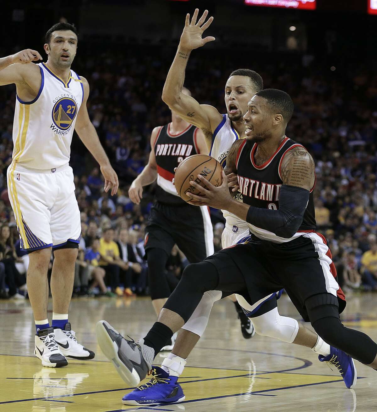 Portland Trail Blazers' Damian Lillard, right, drives the ball as Golden State Warriors' Stephen Curry defends during the first half of a preseason NBA basketball game Friday, Oct. 21, 2016, in Oakland, Calif. At left is Warriors' Zaza Pachulia. (AP Photo/Ben Margot)