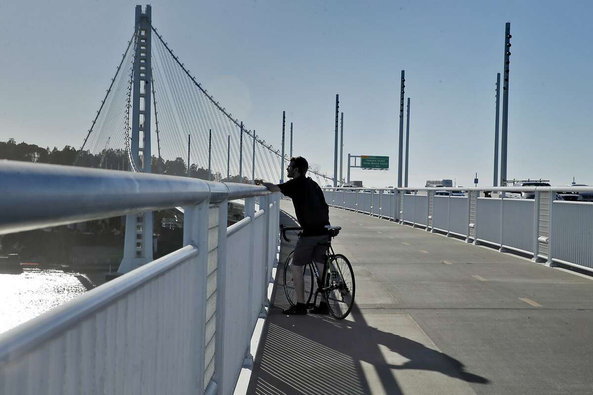 Andy Roth of Berkeley, looks out over the demolition of the old Bay Bridge from the Bicycle Pedestrian Path in Oakland, Calif., on Thursday, October 29, 2015. The Bay Bridge bike path from Oakland to Treasure Island has been delayed yet again. Originally scheduled to open along with the new eastern span two years ago, completion had to wait for demolition of part of the old span, which was to be completed by summer. Then it was delayed until late fall/end of the year. Now, it looks like bike riders won't be able to pedal from the East Bay to Treasure Island until sometime next year.