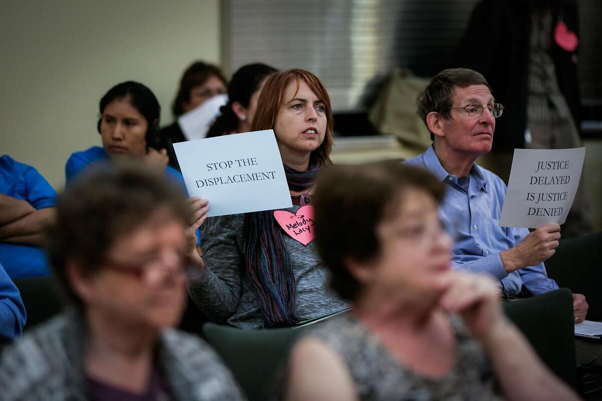 Activist Kristi Laughlin (left) and Bob Lane (right), hold up signs in favor of a housing moratorium, during the Concord City Council's Housing and Economic Development Committee meeting, in Concord, California, on Monday, Oct. 24, 2016.