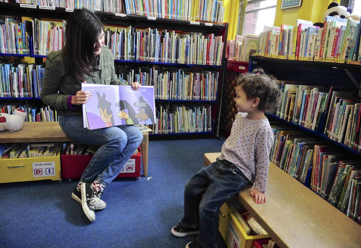 Pattianne Bun, of New Milford, and her daughter Emmaline, age 3, read "Light- Shadows, Mirrors and rainbows" in the children's section of the New Milford Public Library on Tuesday, October 25, 2016, in New Milford, Conn.