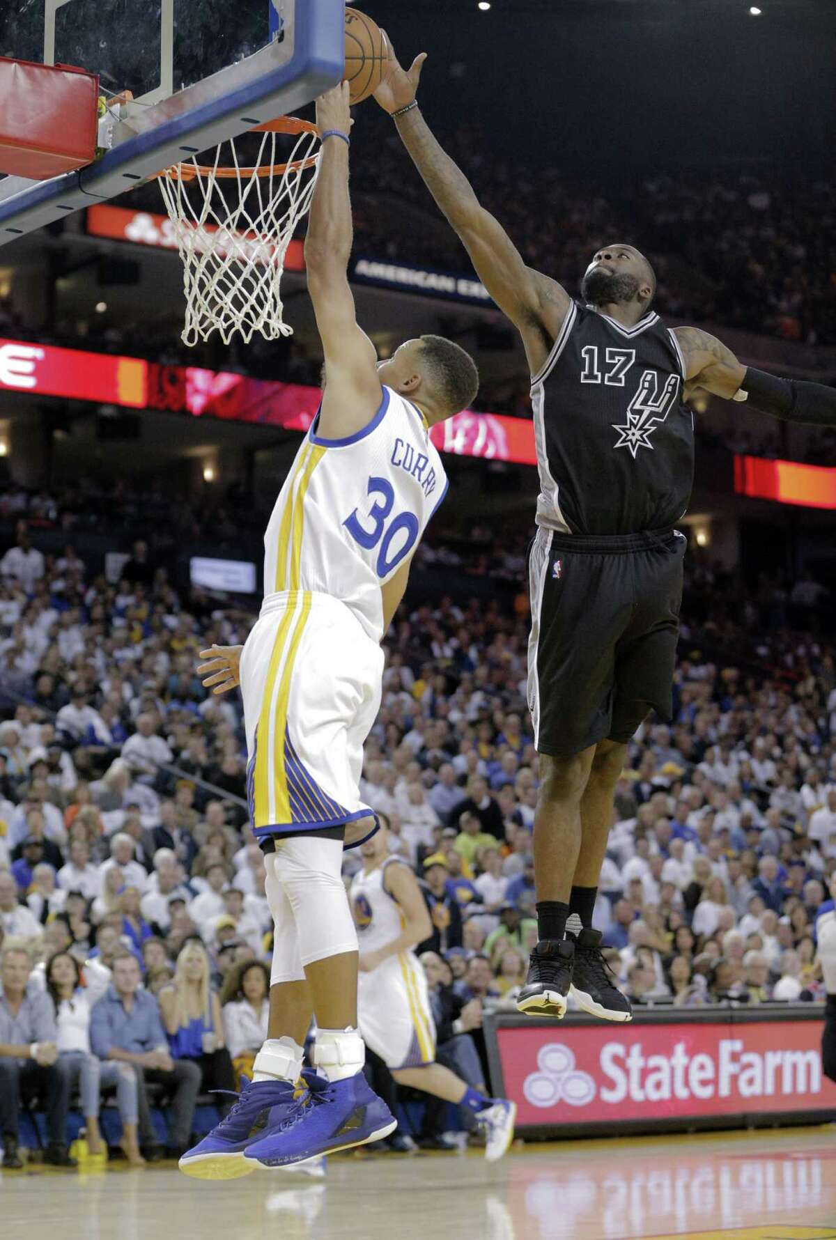 Stephen Curry (30) has his shot blocked by Jonathon Simmons (17) in the second half as the Golden State Warriors played the San Antonio Spurs in their season opener at Oracle Arena in Oakland, Calif., on Tuesday, October 25, 2016.