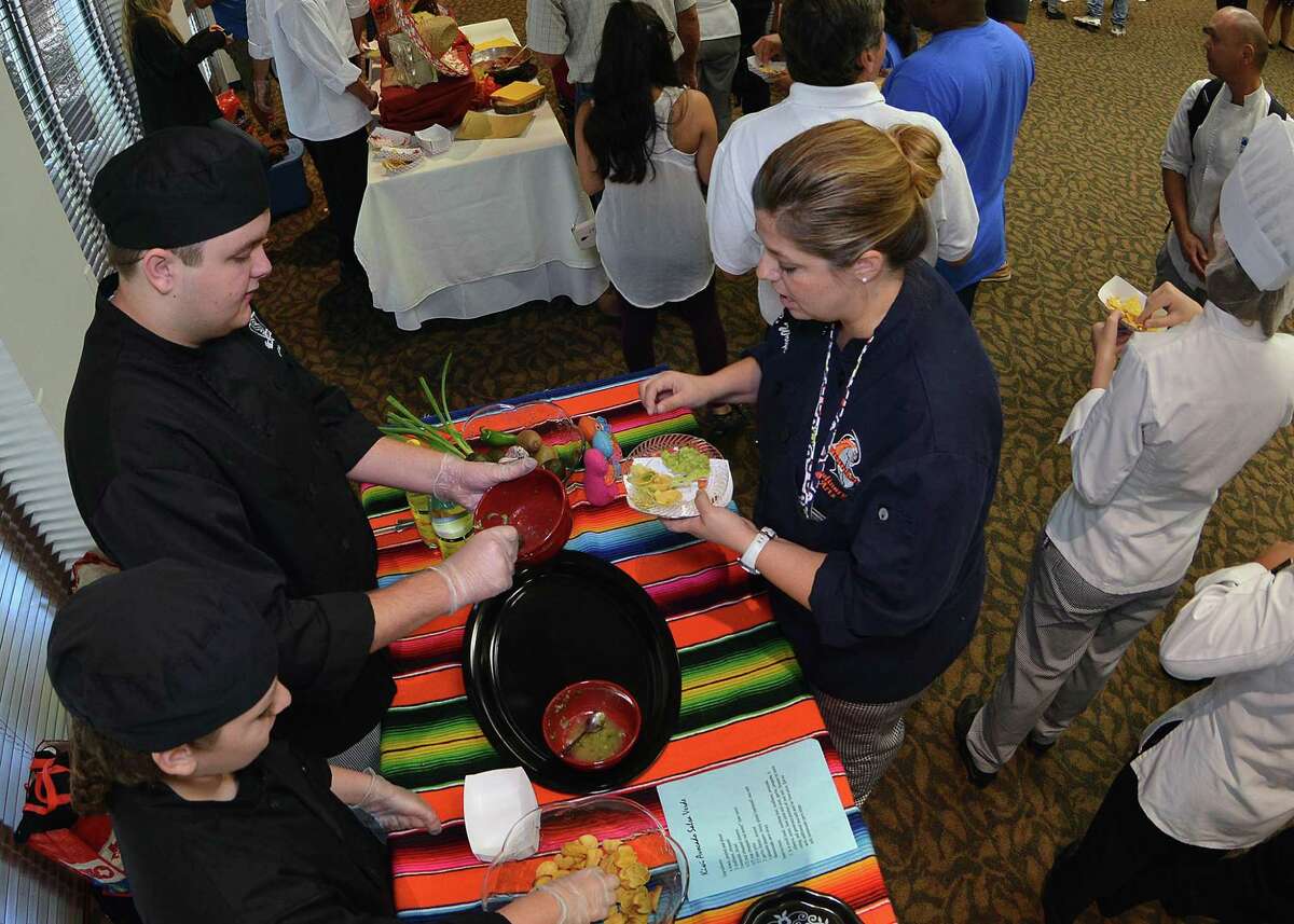 Steele High School students Ty Craighead and Shukria Al Araibi serve their Kiwi Avocado Salsa Verde to an attendee of the Oct. 12 St. Philip's College Best Tasting Salsa Scholarship Competition.