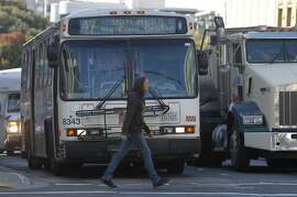 A pedestrian walks past a Muni bus on Van Ness Avenue in San Francisco, Calif. on Thursday, Aug. 27, 2015. Muni is getting ready to roll out a second round of major service improvements systemwide.