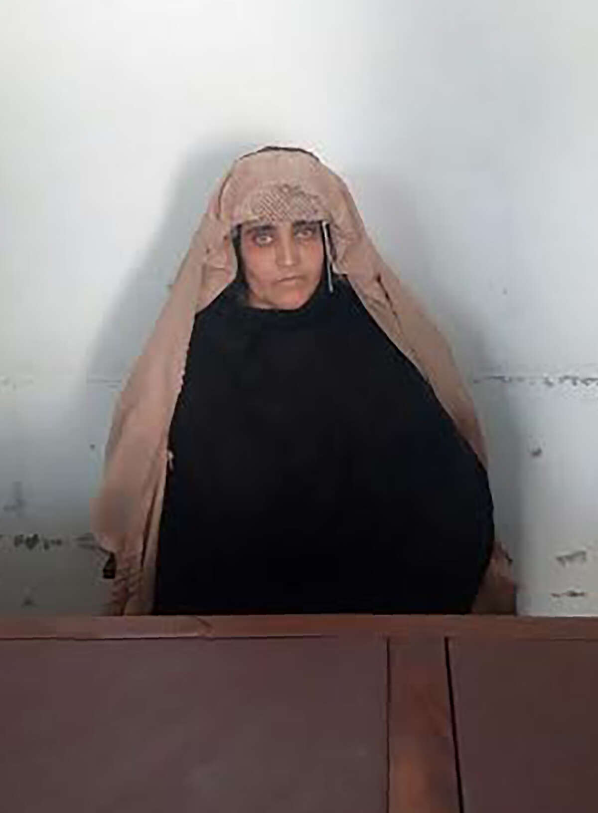At left, Sharbat Gula in her iconic 1984 photo. At right, Gula is shown on Wednesday after her arrest in Pakistan on ID fraud charges.
