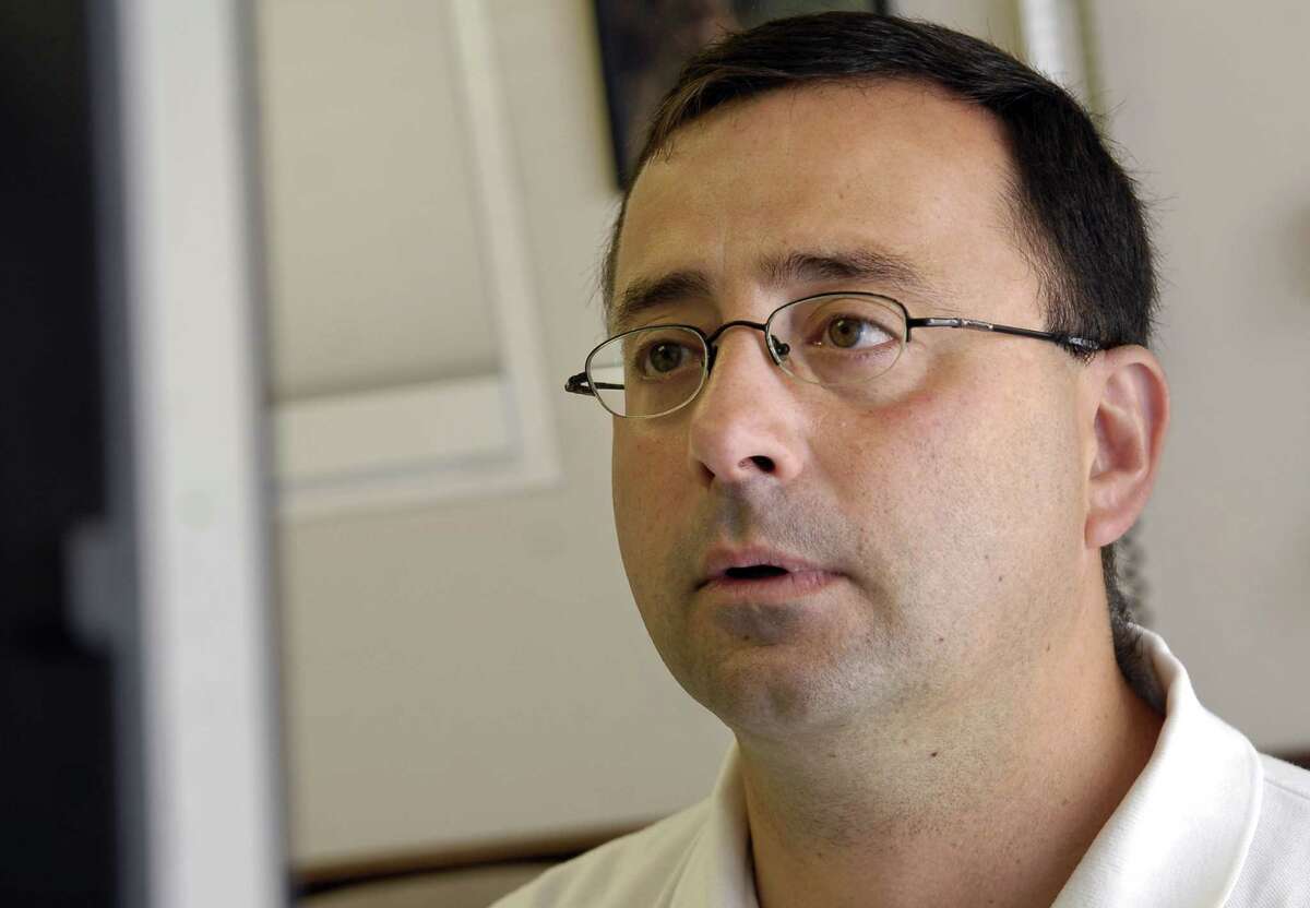 FILE - In this July 15, 2008, file photo, Dr. Larry Nassar works on the computer after seeing a patient in Michigan. Nassar, accused of sexual abuse by two gymnasts, has been fired by Michigan State University, eniversity spokesman Jason Cody said Tuesday, Sept. 20, 2016. (Becky Shink/Lansing State Journal via AP, File)