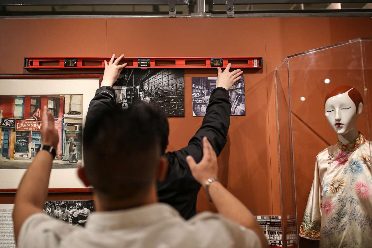 Johnson Zheng (back) and Nolan Chow hang the final touches at the Chinese Historical Society of America's new exhibit "Chinese American Exclusion/Inclusion" at the Chinese History Society Museum on Thursday, Oct 27, 2016 in San Francisco, Calif.