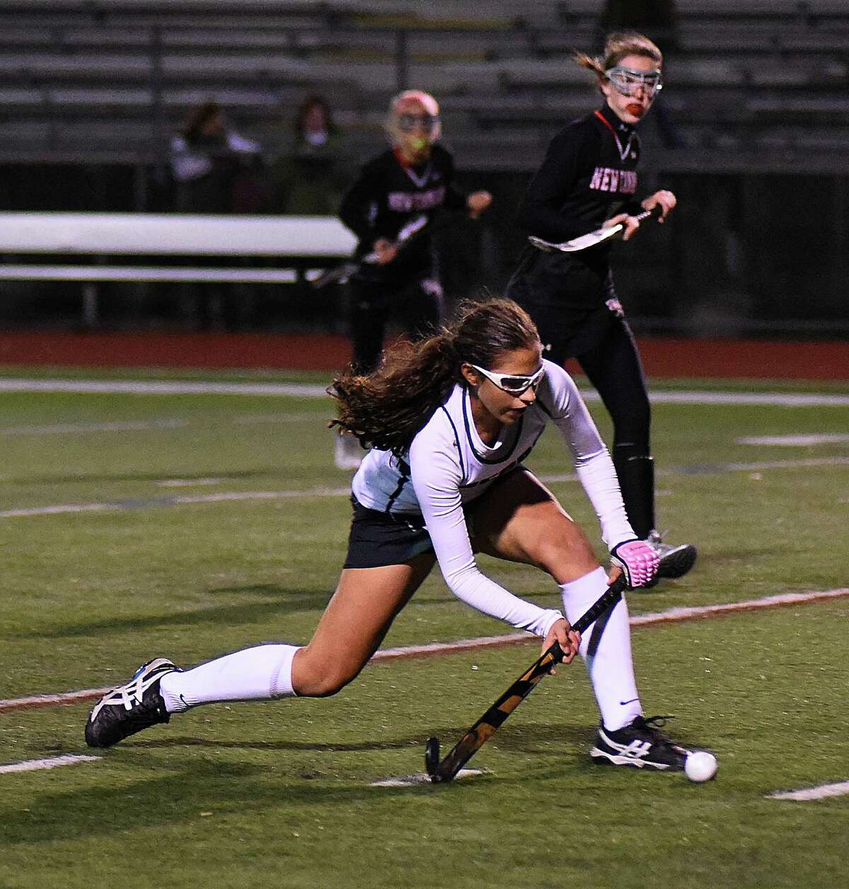 Norwalk's Jacqueline Mirabile, bottom, looks to push the ball into the circle as a pair of New Canaan defenders look on during the second half of Friday night's FCIAC field hockey quarterfinals at Testa Field in Norwalk. The host Bears won the game, 2-1.