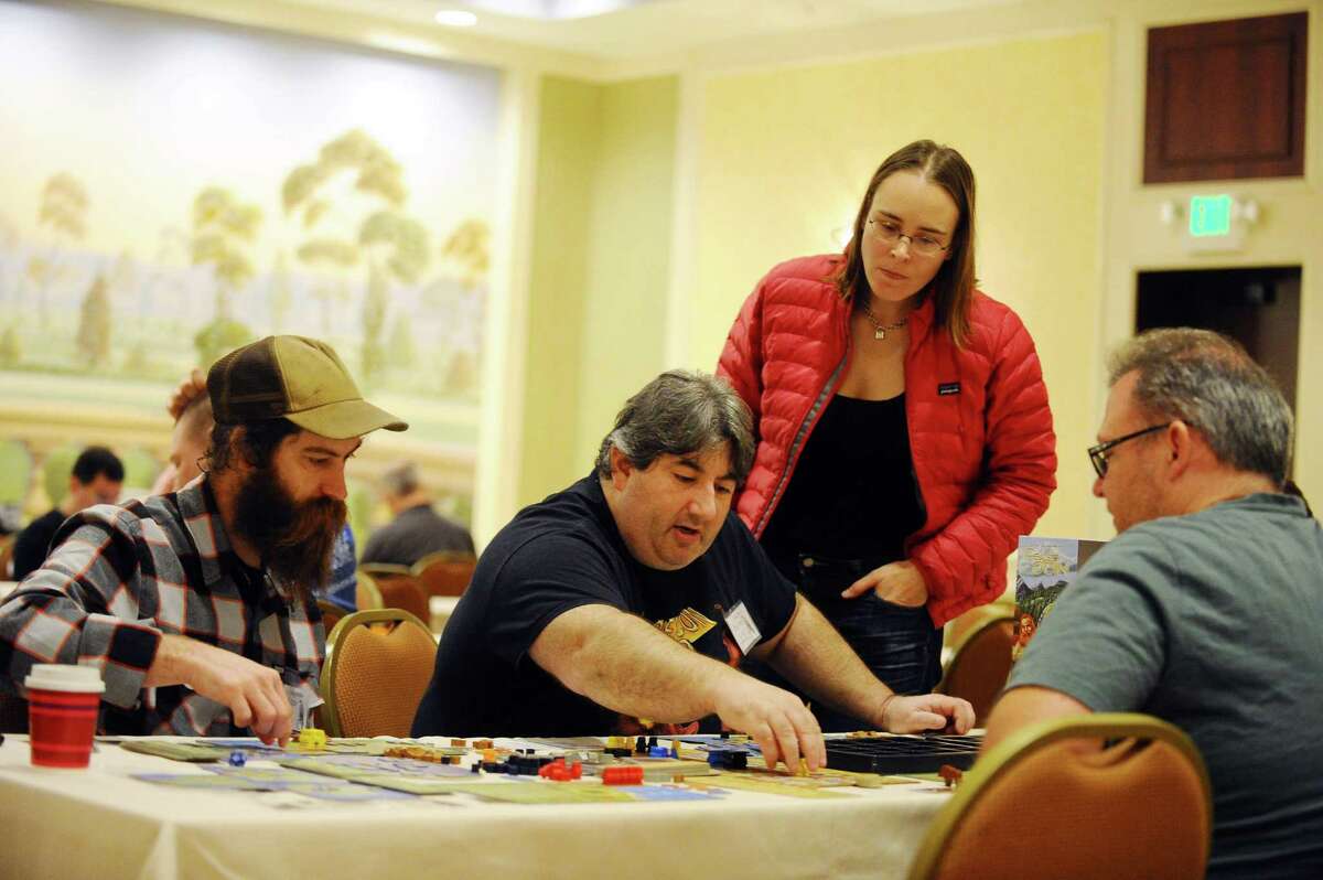 Erick Sklar, center, mmoves his pieces around the board while playing A Feast for Odin during the third day of ConnCon Falcon 2016, a fantasy board, card and role playing game conference inside the Stamford Marriott hotel in Stamford, Conn. on Sunday, Oct. 30, 2016.