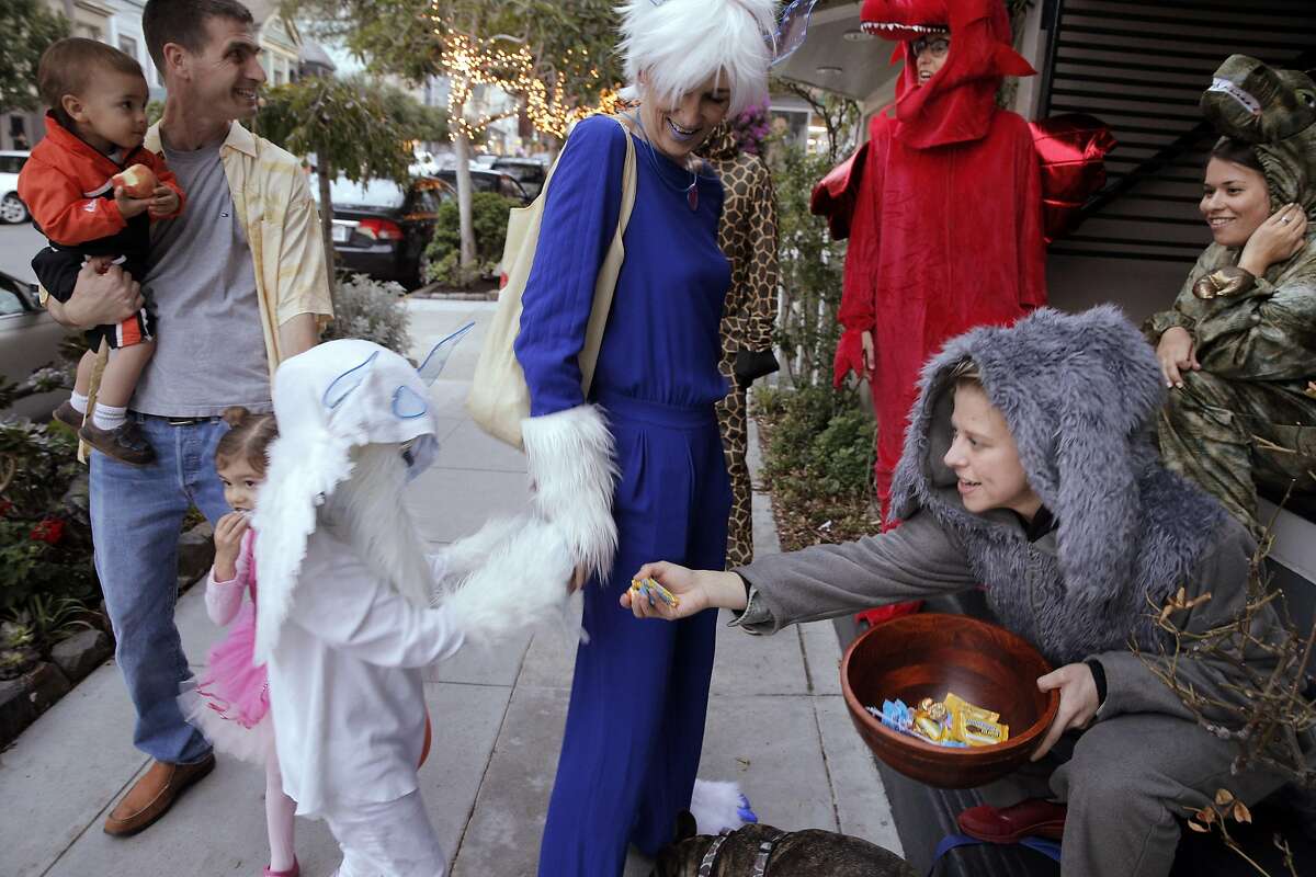 Miles Miesnieks, 7, gets a handful of candy with his mom, Silka, from Marie Van Wassenhoven, right, as they Trick-or-Treat on 24th Stree in Noe Valley as the city celebrated Halloween in San Francisco, Calif., on Monday, October 31, 2016.