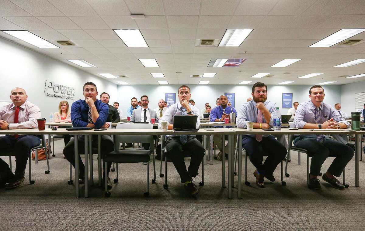 Members of the sales team at Power Home Remodeling watch a presentation during a weekly meeting.