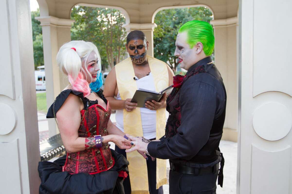 Nicole and John Fowler dressed as Harley Quinn and the Joker for their wedding at King William Park, surrounded by a their loved ones, also dressed as comic book characters.