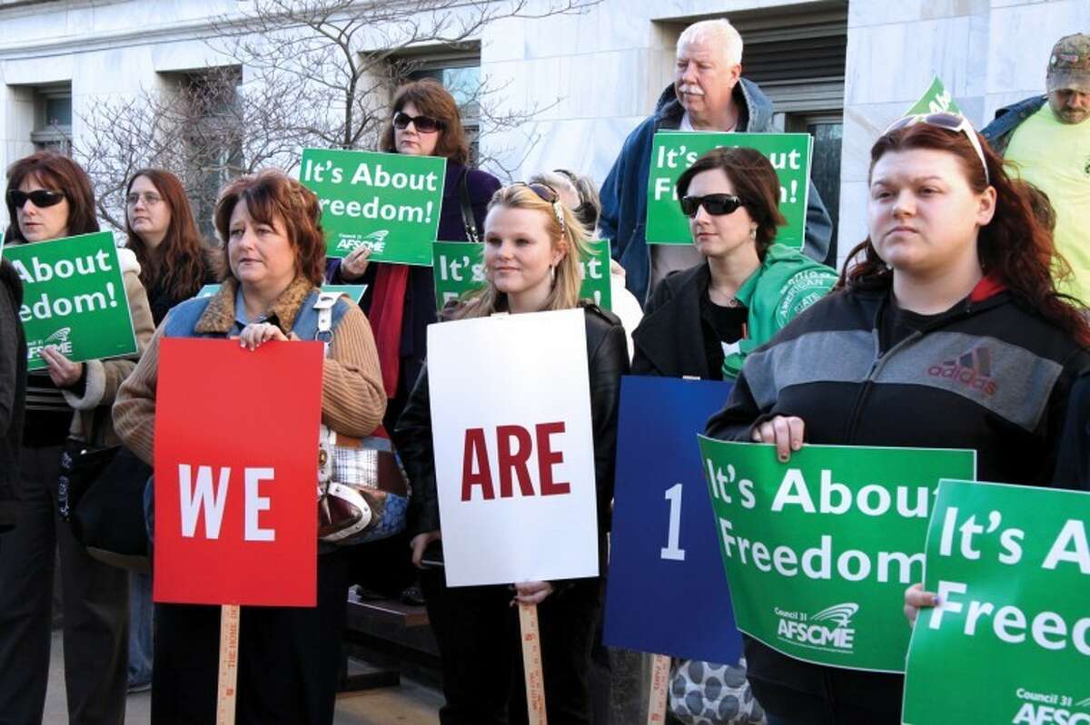 Kim Bardill, Lexy Schlemer, Sami Brenner and Ashley Cloninger, pictured in front, with AFSCME, hold signs of support and unity during a rally at the courthouse plaza Wednesday afternoon.
