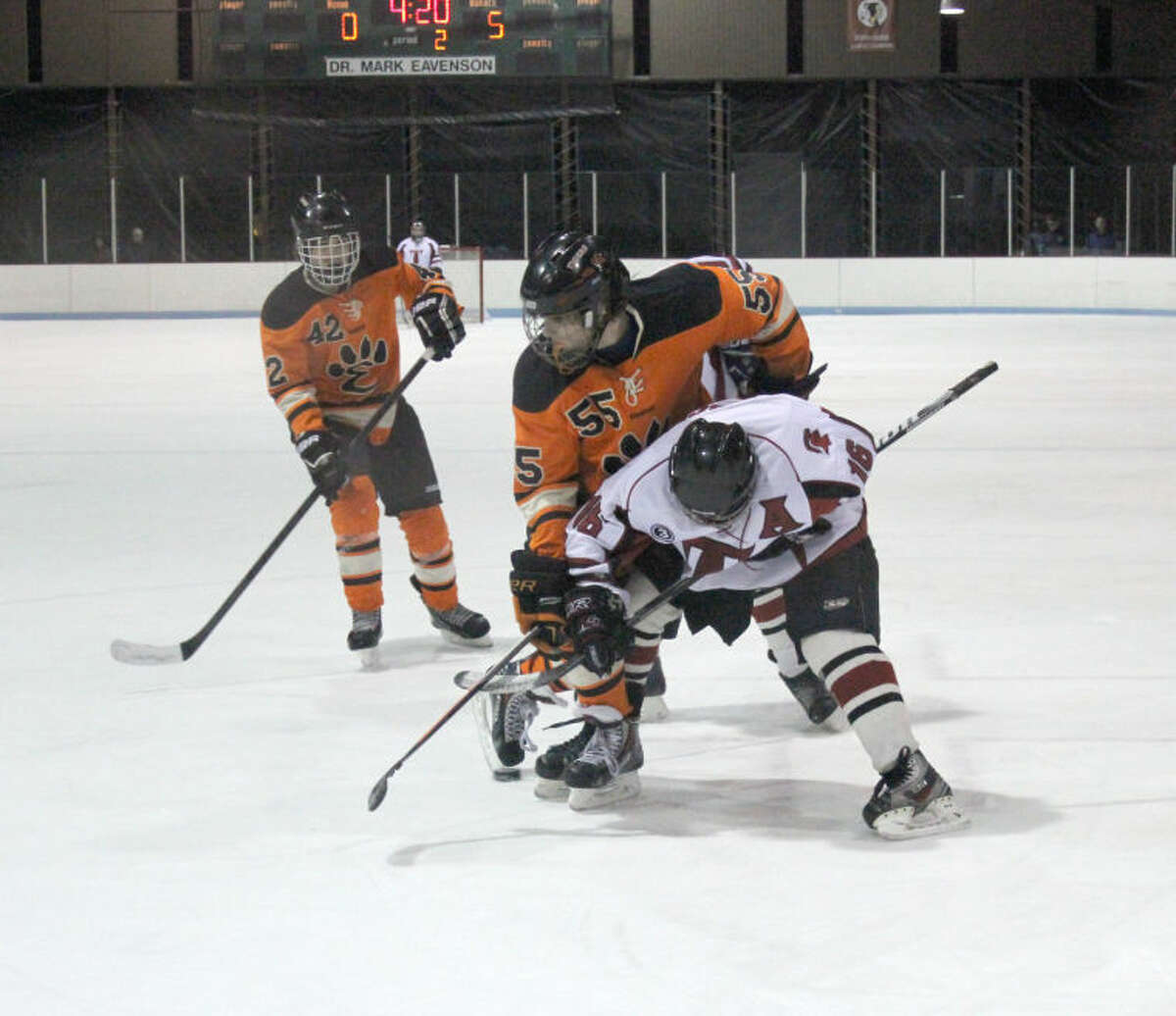 Edwardsville’s Shaun Raftery (No. 55) batlles for a loose puck on Thursday in Granite City.