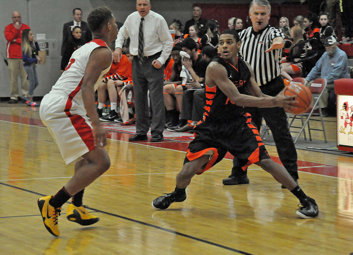 Edwardsville’s Chrys Colley, left, shields the ball away from an Alton defender near midcourt on Friday in Alton. 