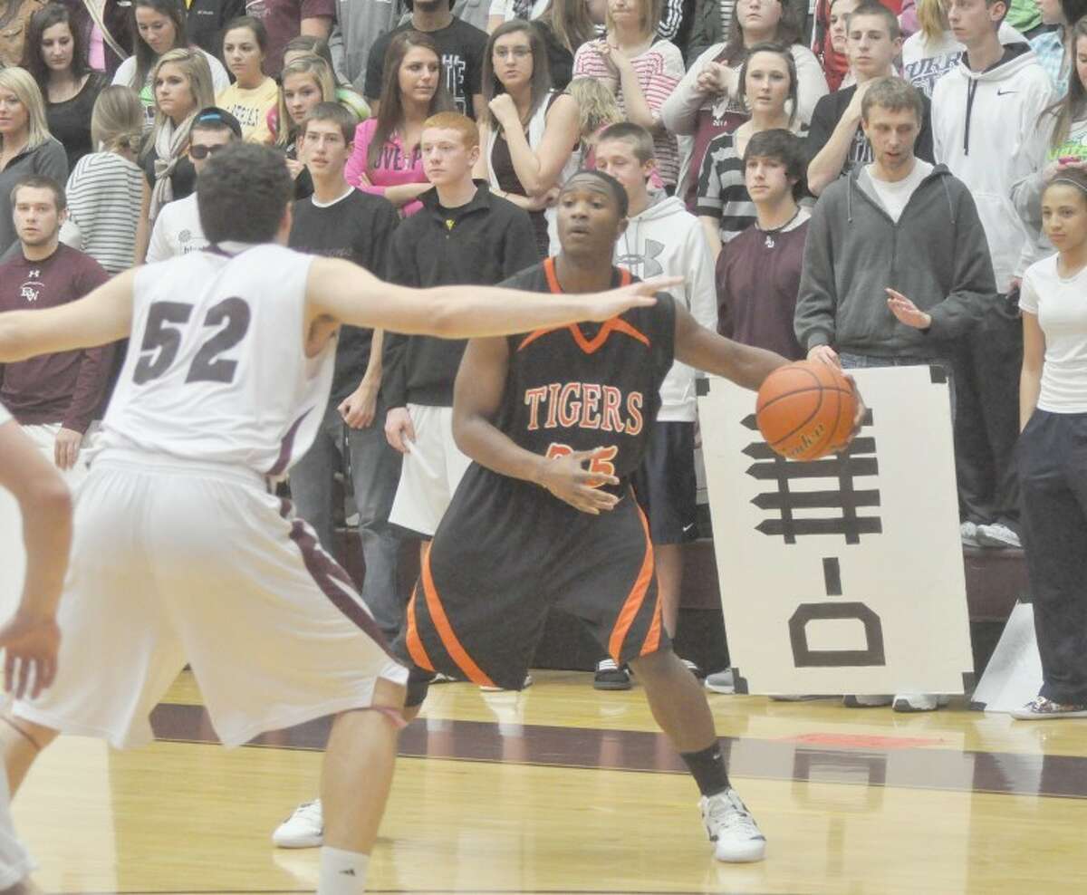 Tiger Diarra Cropper looks for an open teammate while shielding the ball away from Maroon Kendall Smith in front of the Belleville West student section. The Tigers moved into second place in the conference with a 58-55 win.
