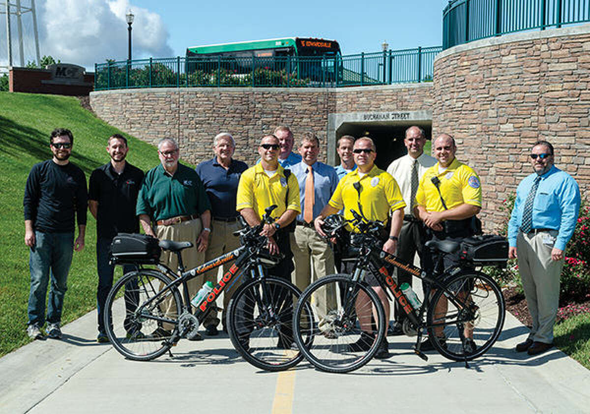 Employees from The Cyclery and Fitness Center, Chairman of the MCT Board of Trustees Dan Corbett, MCT Managing Director Jerry Kane, members of the Edwardsville Police Department, Edwardsville Mayor Hal Patton and City Administrator Tim Harr pose for a picture with the two donated bikes on the Nickel Plate Trail.