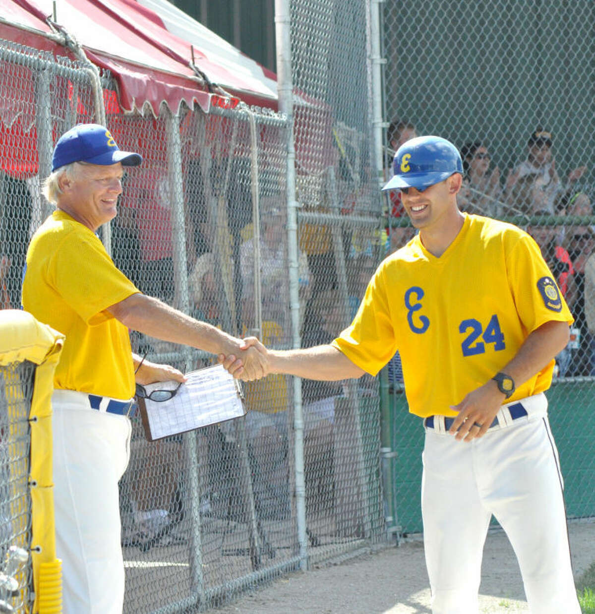 Post 199 head coach Ken Schaake, left, is all smiles while shaking hands with first base coach Jake Schaake, right, following the win over Moline. Ken Schaake is drenched in water from taking a cooler bath provided by Post 199’s Devin Breihan.