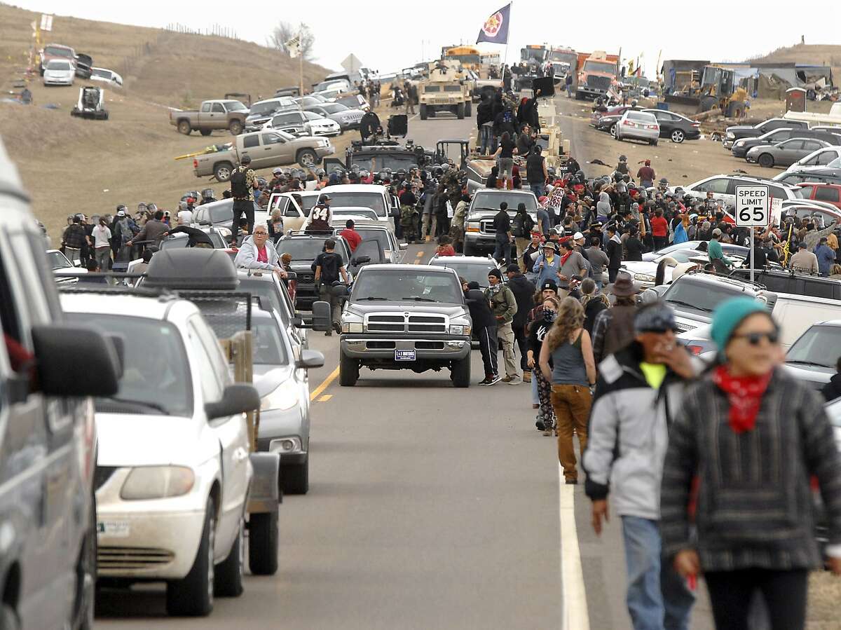An exodus of Dakota Access Pipeline protesters move south on Highway 1806 as a line of law enforcement slowly push the protest effort from the Front Line Camp to the Oceti Wakoni overflow camp a few miles down the road in Morton County, N.D., Thursday, Oct. 27, 2016. (Mike McCleary/The Bismarck Tribune via AP)