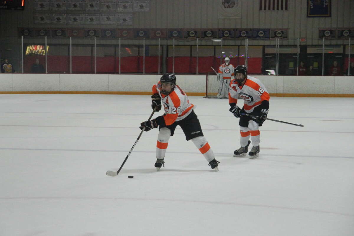 Edwardsville’s Rory Margherio skates into the neutral zone while John Paul Krekovich, 16, and goalie Matthew Griffin watch on.