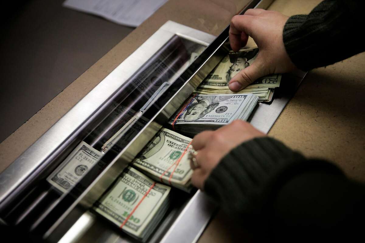 A woman who owns a cannabis delivery service slips her money through a cashier window as she pays her taxes in cash to the Board of Equalization in Oakland, California, on Monday, Oct. 31, 2016. She paid $31,500 in cash.
