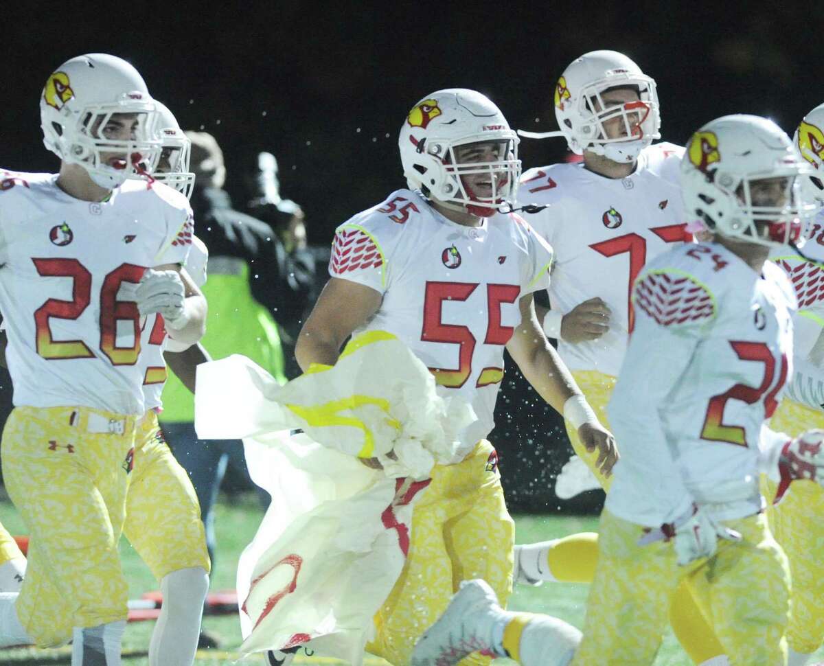 Jake Cohen (55) and Christian Novakowski (77) lead the Cardinals on to the field for a game at New Canaan on Oct. 21.