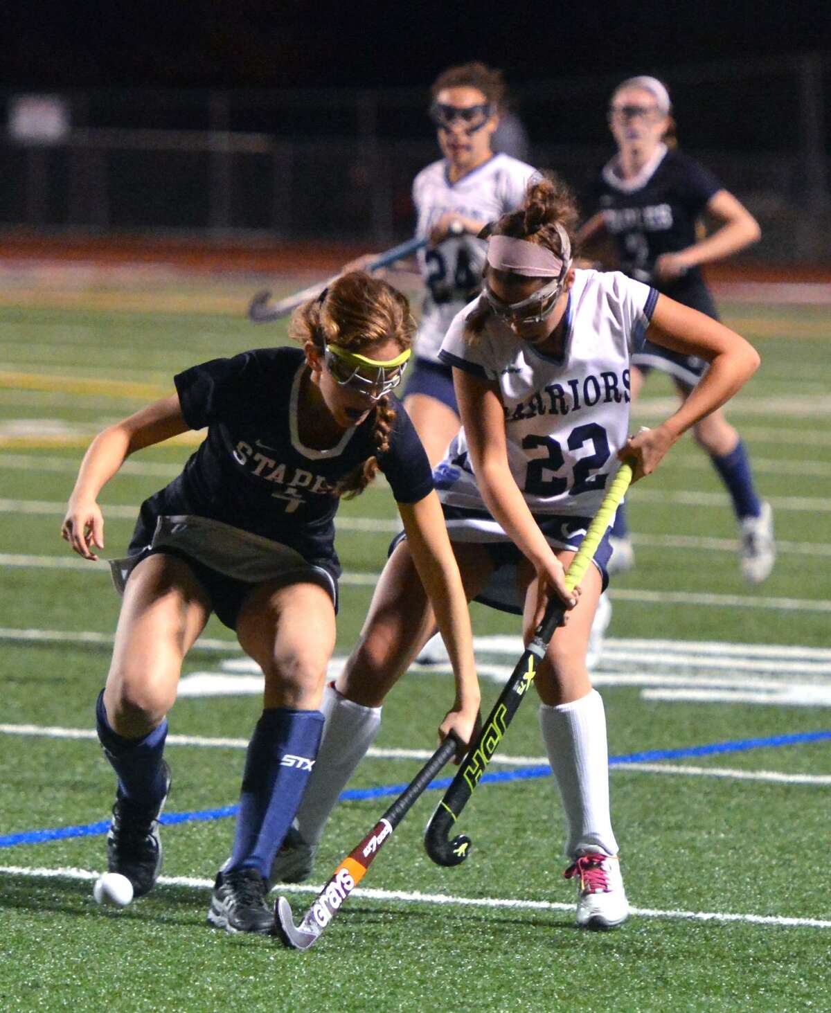 Staples’ Grace Cooper (4) keeps the ball away from Wilton's Olivia Hahn (22) in the FCIAC championship girls field hockey game Thursday at Brien McMahon High School in Norwalk.