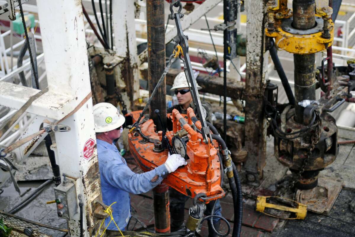 Kevin Giddings, left, and Noe Olvera, right, add a section of casing down a vertical well on the floor of Trinidad Rig 433 on Wednesday, Nov. 2, 2016, in Midland County. James Durbin/Reporter-Telegram
