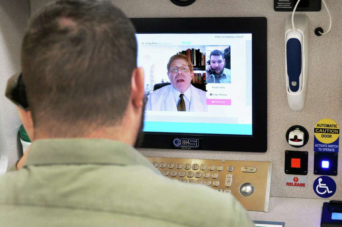 Store pharmacist Michael Zappone, left, speaks with Dr. Craig Price of New Jersey during a demonstration of a new telemedicine option “Doctor on Demand” in New Jersey. The option in Texas is hampered by outdated regulations.