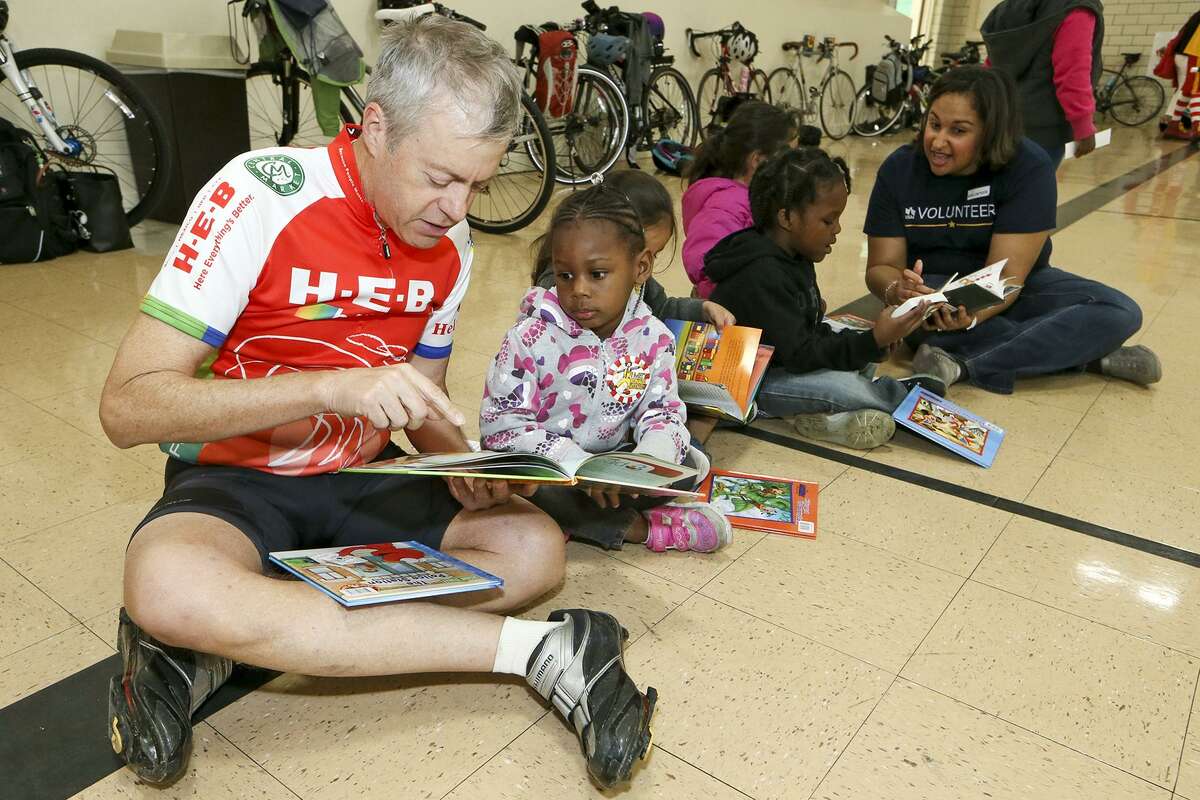 Robert Alston (left) reads a book to Serenity Satterwhite, 3, as cyclists with Ride for Reading delivered books and provided tricycle safety tips to preschoolers at the Carroll Early Childhood Center. Approximately 40 volunteers from USAA and H-E-B participated in the organization's inaugural delivery in San Antonio, bringing 650 books to the children. "We need to get books into the hands of children," said Stephanie Ward, spokeswoman for the group.