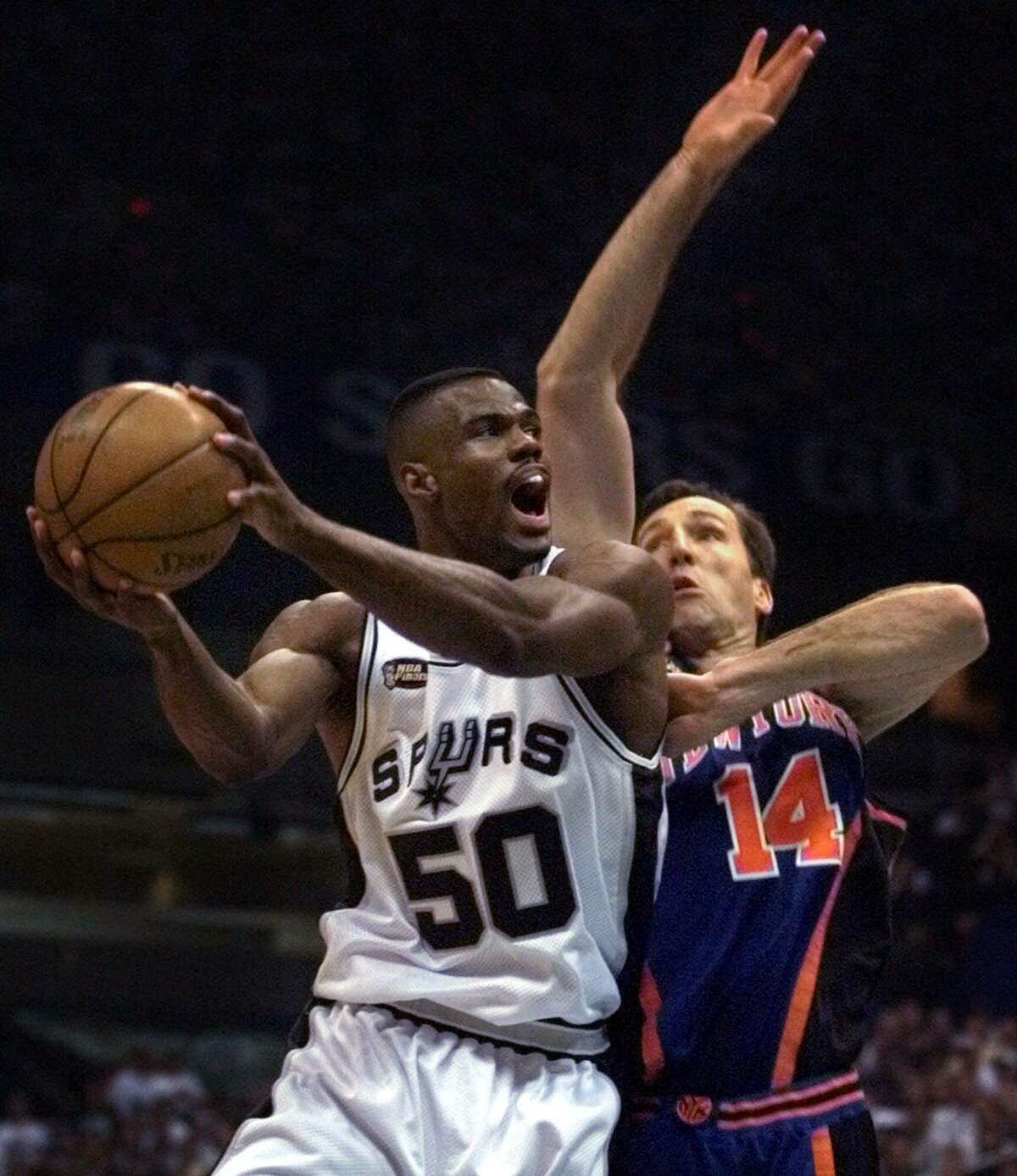 Allan Houston of the New York Knicks shoots against Tim Duncan of