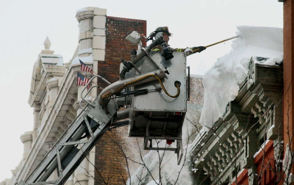 Dec. 6-7, 2003: A system lingered over the Capital Region long enough to drop 18 inches of snow on Albany, and 32 inches in Averill Park. Troy Fire Department Lt. Tom Scorsone stands in Ladder Truck 2 while using a pike pole to remove snow hanging four stories over the entrance to the Arts Center of the Capital Region in Troy on Dec. 7, 2003.