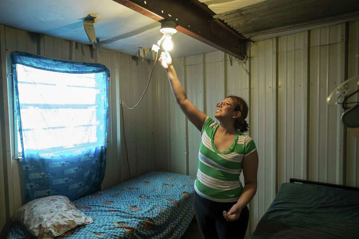 Nora Castillo, 31, reaches up to unscrew a light bulb to turn it off in the two bedroom living space she and her family share in O'Donnell, Texas, on Aug.19, 2015. Throughout the Panhandle and West Texas, motels often serve as housing of last resort for farmworkers. (Rodolfo Gonzalez/Austin American-Statesman via AP) AUSTIN CHRONICLE OUT, COMMUNITY IMPACT OUT, INTERNET AND TV MUST CREDIT PHOTOGRAPHER AND STATESMAN.COM, MAGS OUT; MANDATORY CREDIT