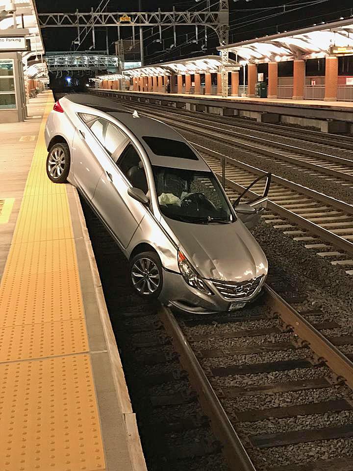 Man drives car onto railroad tracks at station