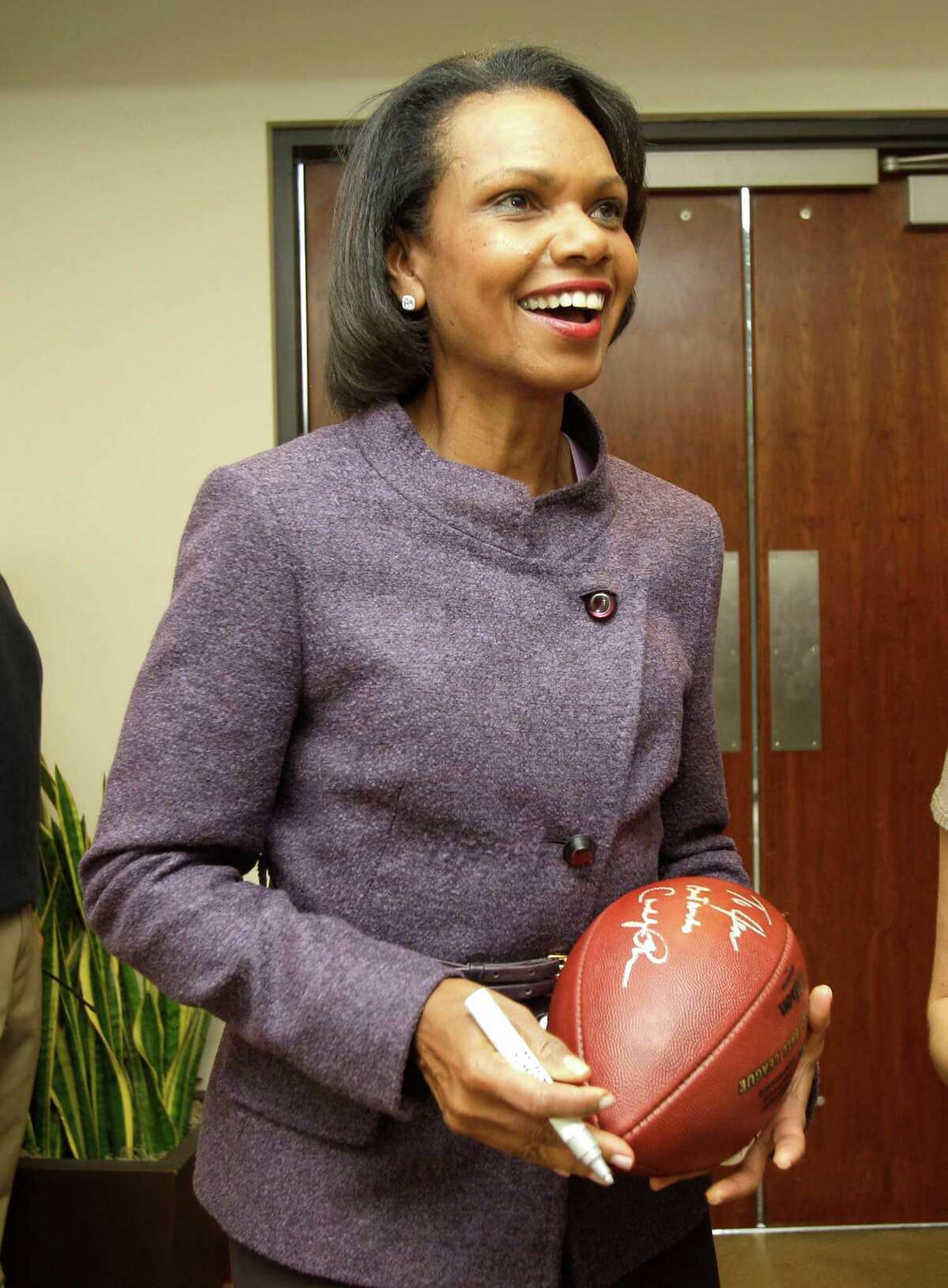 In this Oct. 10, 2010, file photo, former Secretary of State Condoleezza Rice laughs after autographing a football following her visit with the Cleveland Browns coaches and players at the team's NFL football training facility in Berea, Ohio. A person with direct knowledge of the process tells The Associated Press on Friday, Oct. 4, 2013, that Rice is expected to be part of the selection committee that will pick the teams for the College Football Playoff next year. The person spoke on condition of anonymity because the selection process is still ongoing. (AP Photo/Amy Sancetta, File)