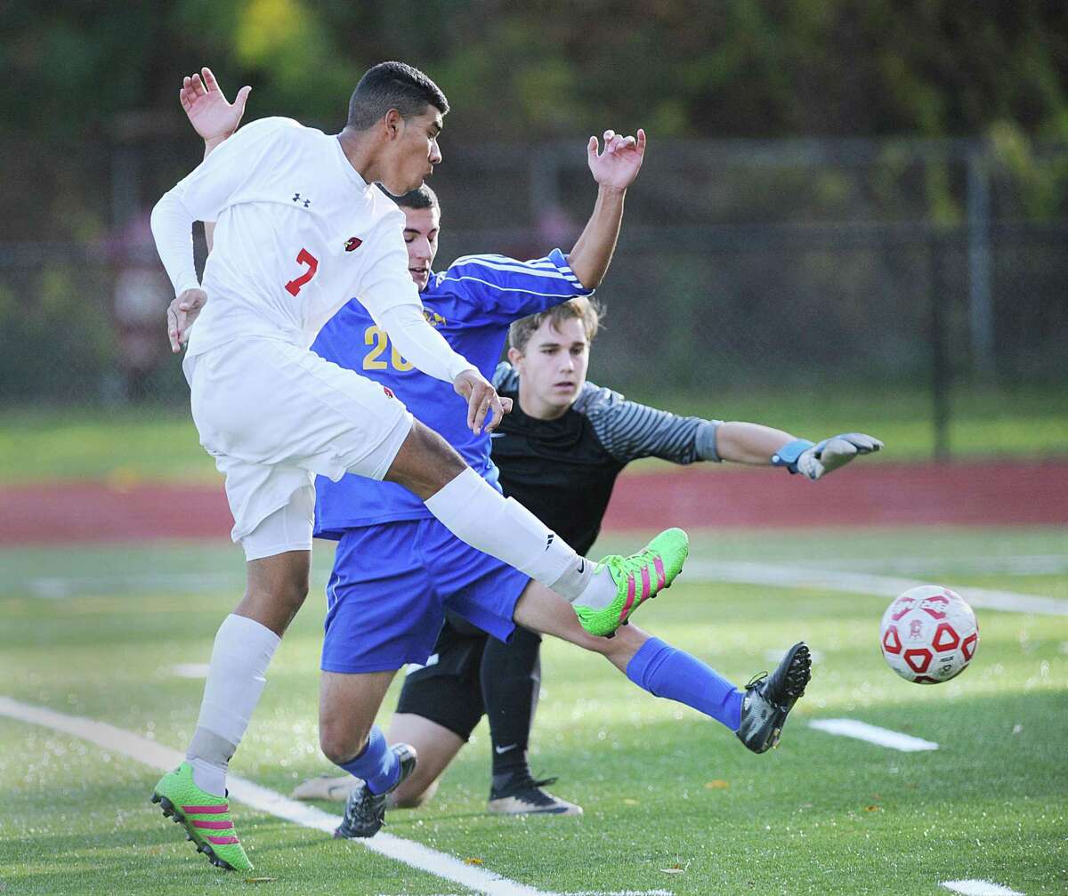 At left, Sebastian Hernandez of Greenwich gets off a shot that gets past Newtown keeper Cameron Trivers, right, for the first goal of the match during the boys high school Class LL soccer playoff game between Greenwich High School and Newtown High School at Cardinal Stadium in Greenwich, Conn., Thursday, Nov. 10, 2016. At center defending for Newtown is Hunter Procaccini. Greenwich advanced in the tournament, defeating Newtown 2-1.