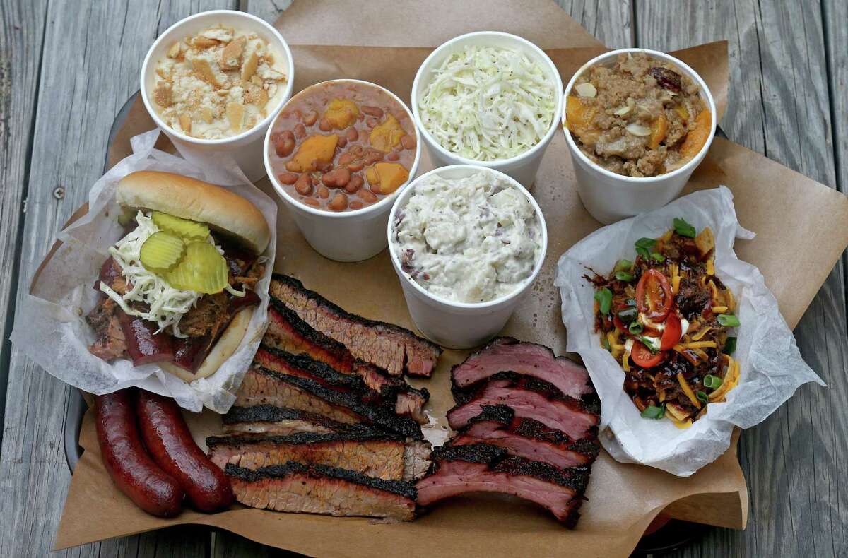 Sausage (from left clockwise), Big Bro Sandwich, banana pudding, beans, potato salad, cole slaw, peach cobbler, chopped beef Frito pie, cherry glazed baby back ribs and brisket from Two Bros. BBQ Market