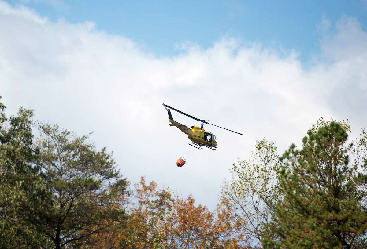 A helicopter carrying 240 gallons of water takes off to assist in the fire containment efforts Wednesday, Nov. 10, 2016 at Lake Lure, N.C. Unseasonably warm dry weather has deepened a drought that's igniting forest fires across the southeastern U.S. (Abigail Margulis/The Asheville Citizen-Times via AP) ORG XMIT: NCASH101