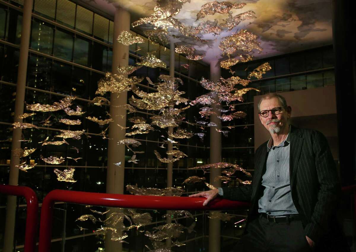 Artist Ed Wilson stands by his new sculpture, "Soaring in the Clouds," inside the new grand lobby of the George R. Brown Convention Center in downtown Houston, Thursday, Nov. 10, 2016. The sculpture is made of many small pieces suspended from the almost 100-foot-high ceiling and lit by constantly changing colors. (Mark Mulligan/Houston Chronicle via AP)