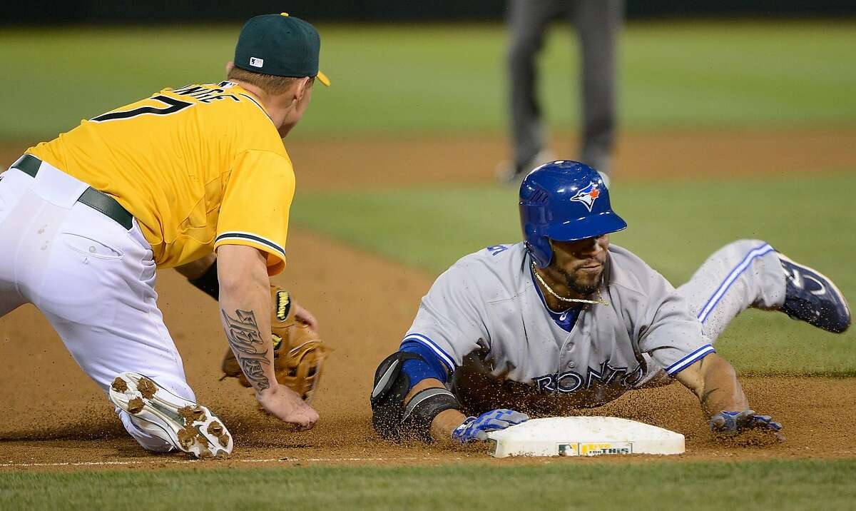 OAKLAND, CA - MAY 08: Eric Thames #14 of the Toronto Blue Jays slides into third base head firs with a triple beating the throw to Brandon Inge #7 of the Oakland Athletics in the ninth inning at O.co Coliseum on May 8, 2012 in Oakland, California. The Athletics won the game 7-3 on a walk off grand-slam by Brandon Inge in the bottom of the ninth inning. (Photo by Thearon W. Henderson/Getty Images)