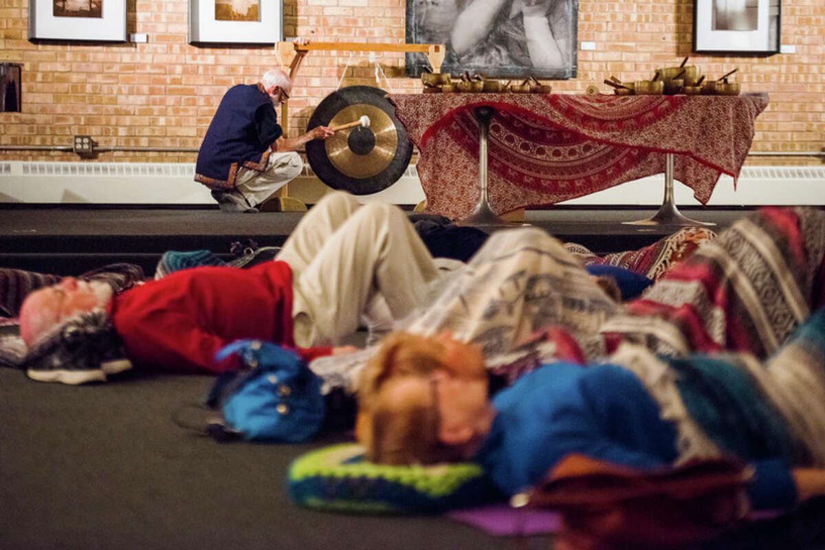 DANIELLE McGREW TENBUSCH | for the Daily News Participants relax and meditate as Amrit Yoga instructor and meditative recording artist Mark Handler, back, rings a gong during a Antique Tibetan Bowl and Chant Concert at Creative 360 in Midland on Friday.