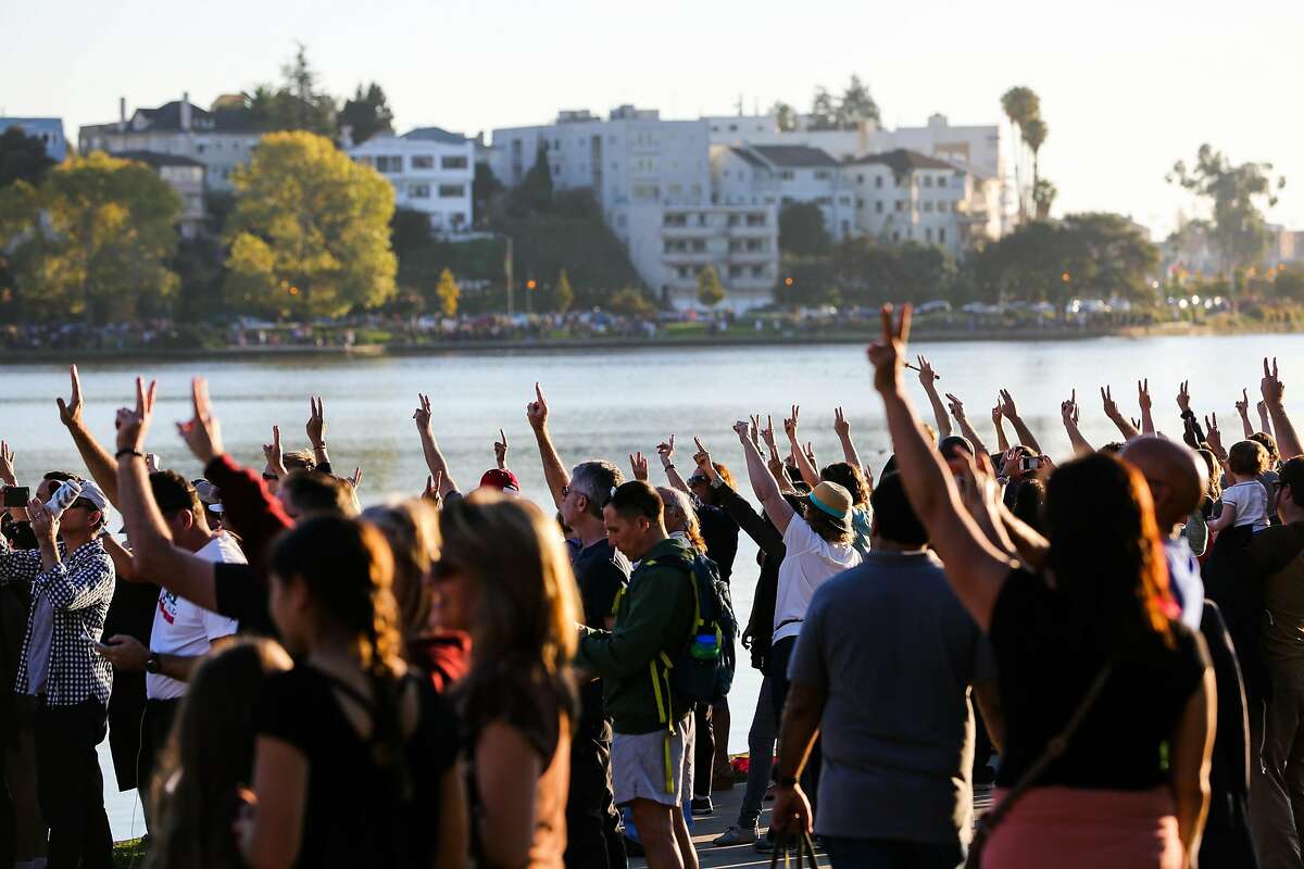 Hundreds hold up the peace sign as they gather during an anti-Trump protest around Lake Merritt, in Oakland, California, on Sunday, Nov. 13, 2016.
