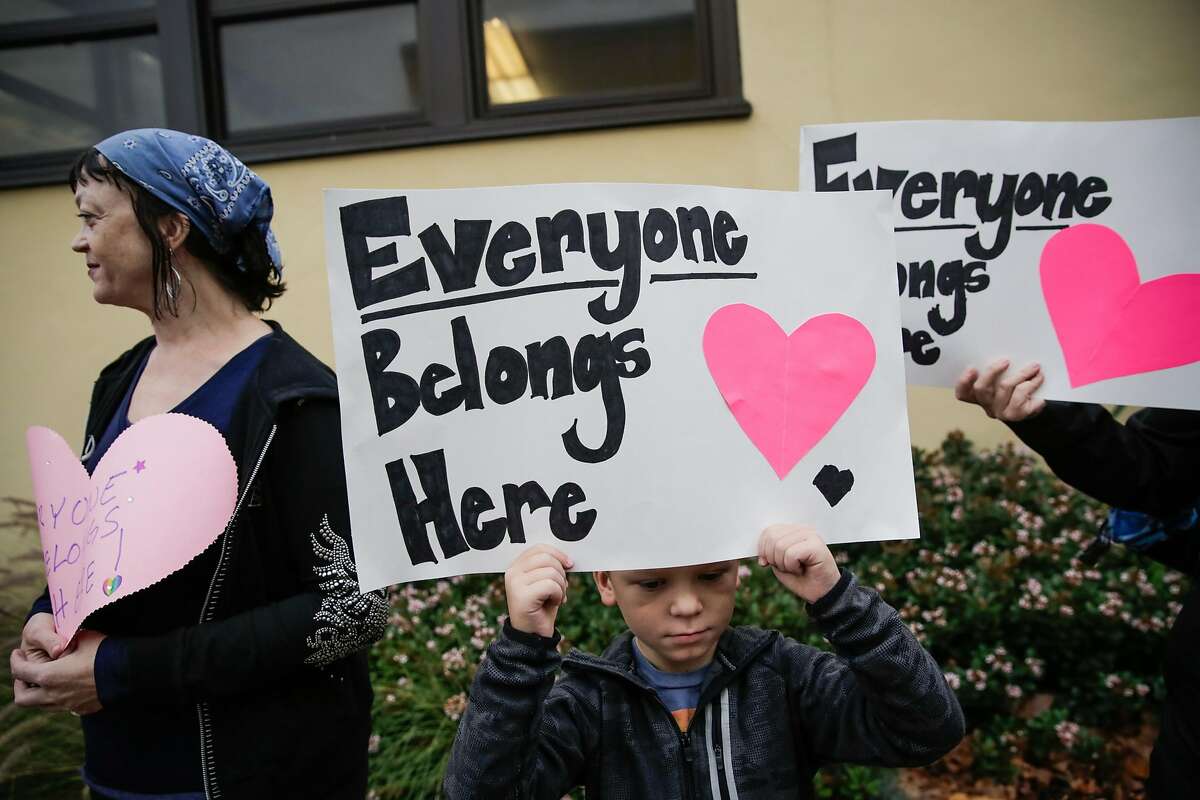 Student Evan Hackett, 7, held up a sign reading "Everyone Belongs Here" over is head as he greeted students who walked into Edison Elementary school on Monday morning, following an incident where racist graffiti was written on exterior of the school, in Alameda, California, on Monday, Nov. 14, 2016.