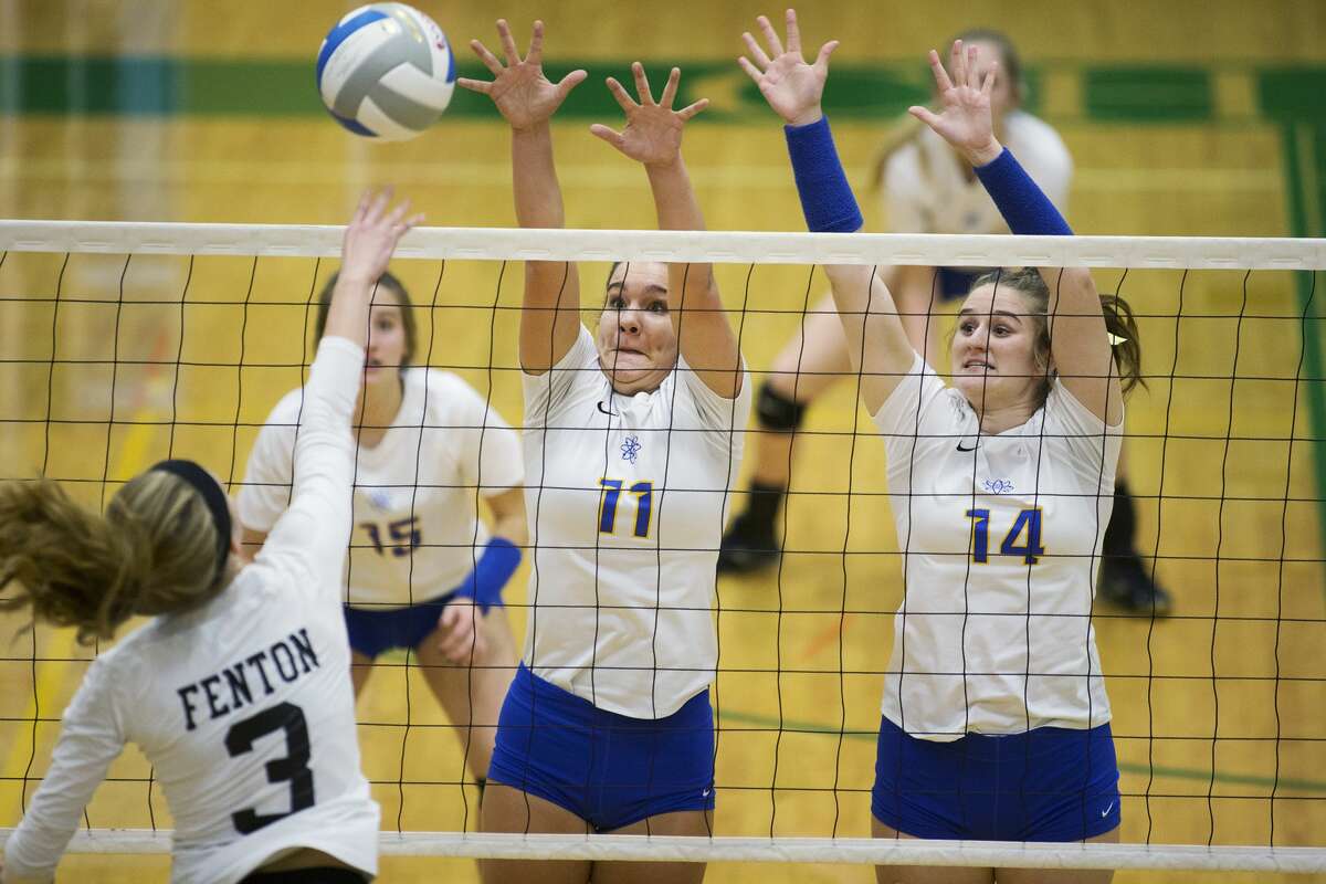 Midland High School junior Alexandria McMath, center, and senior Erin Sheridan, right, attempt to block Fenton senior Jess Warford, left, in the Class A volleyball quarterfinals at Dow High School on Tuesday.